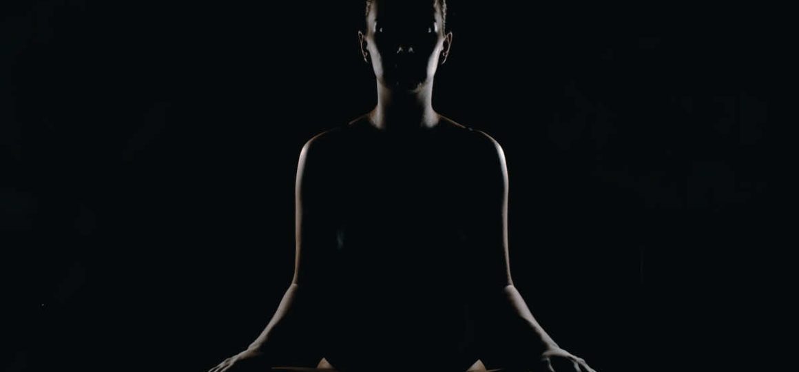 Silhouette of a woman doing seated yoga meditation.
