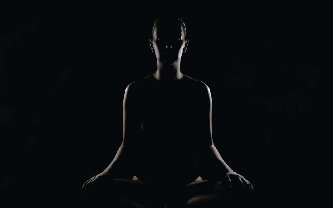 Silhouette of a woman doing seated yoga meditation.