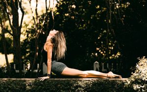 A woman on a jungle wall, doing a serpent yoga pose.