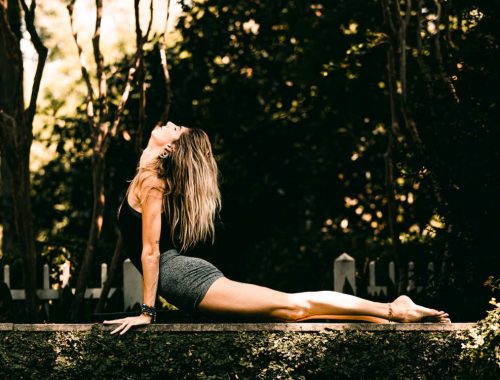 A woman on a jungle wall, doing a serpent yoga pose.