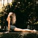 A woman on a jungle wall, doing a serpent yoga pose.